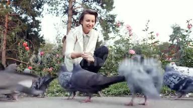 年轻漂亮的女孩在公园里喂鸽子。 <strong>一群</strong>鸟在<strong>户外</strong>吃面包